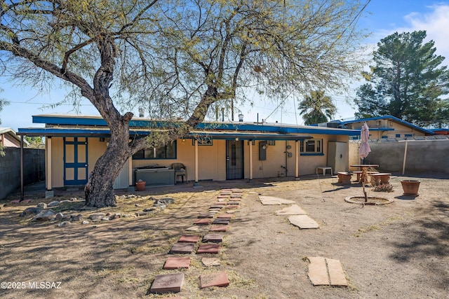 back of house with a hot tub, a patio area, and an outdoor fire pit