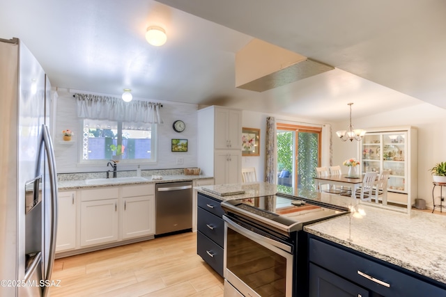 kitchen featuring sink, stainless steel appliances, light stone counters, white cabinets, and decorative light fixtures