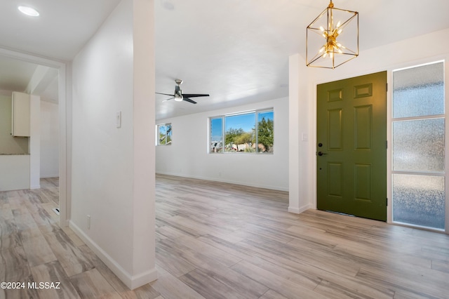 foyer featuring ceiling fan with notable chandelier and light hardwood / wood-style floors