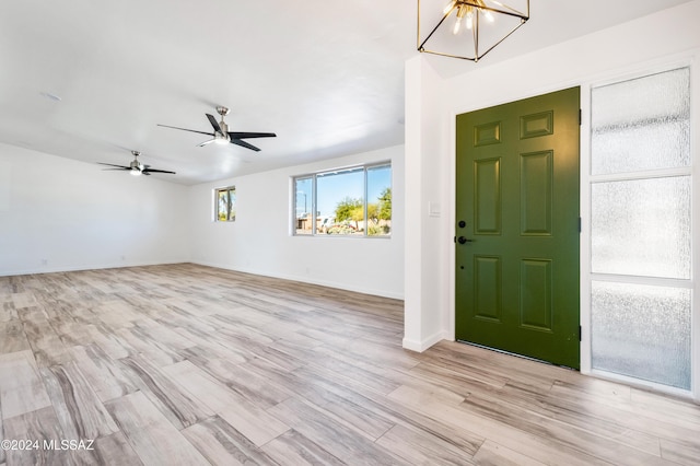 foyer entrance with ceiling fan with notable chandelier and light hardwood / wood-style flooring