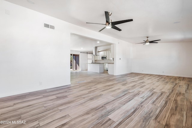 unfurnished living room with light hardwood / wood-style flooring and ceiling fan