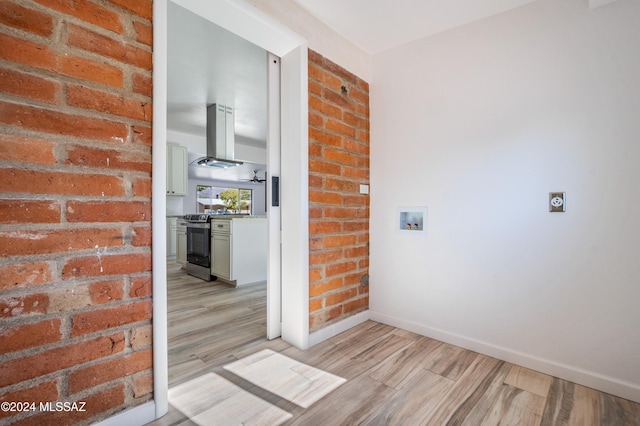 hallway with brick wall and light hardwood / wood-style floors