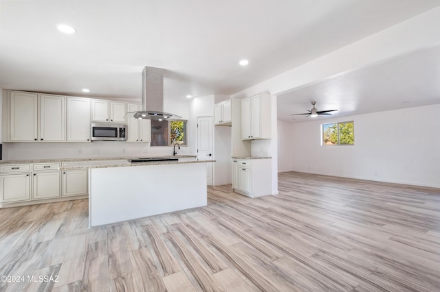 kitchen with island exhaust hood, a center island, light wood-type flooring, and white cabinets