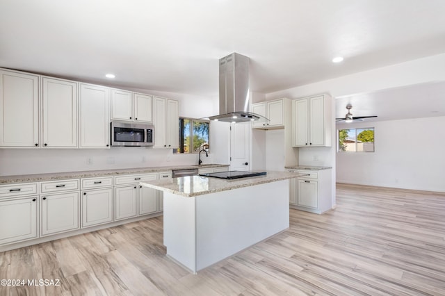 kitchen with island exhaust hood, a kitchen island, ceiling fan, stainless steel appliances, and white cabinets