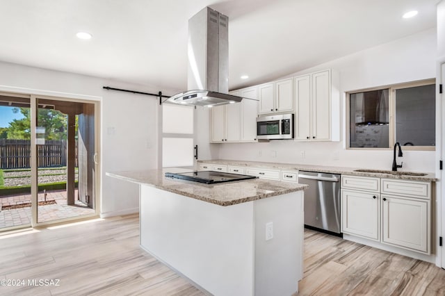 kitchen featuring sink, white cabinetry, stainless steel appliances, island exhaust hood, and a barn door