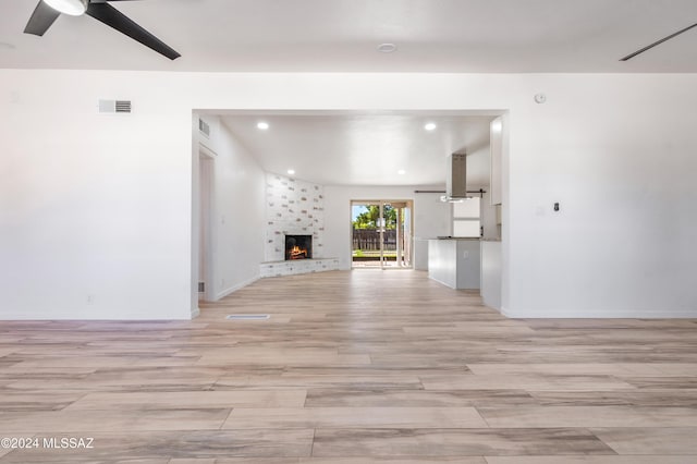 unfurnished living room featuring ceiling fan and a fireplace