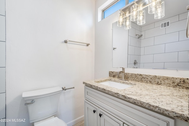 bathroom with vanity, a tile shower, and toilet