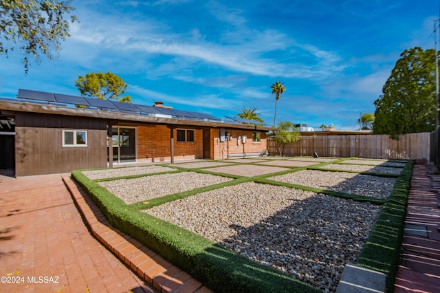 rear view of house featuring a patio and solar panels