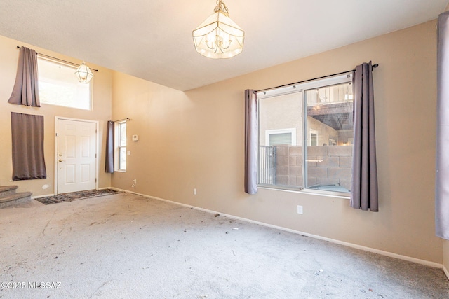 carpeted foyer entrance with an inviting chandelier and plenty of natural light