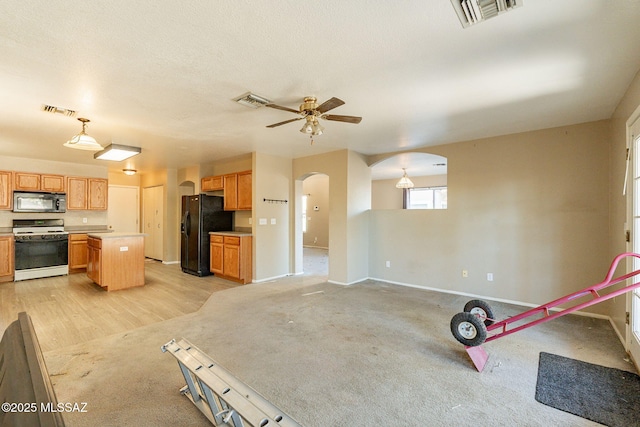 kitchen featuring ceiling fan, black appliances, a kitchen island, decorative light fixtures, and light colored carpet