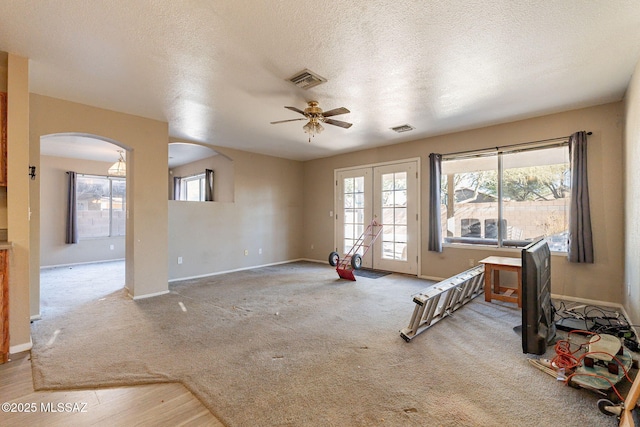 unfurnished room featuring a healthy amount of sunlight, light carpet, a textured ceiling, and french doors