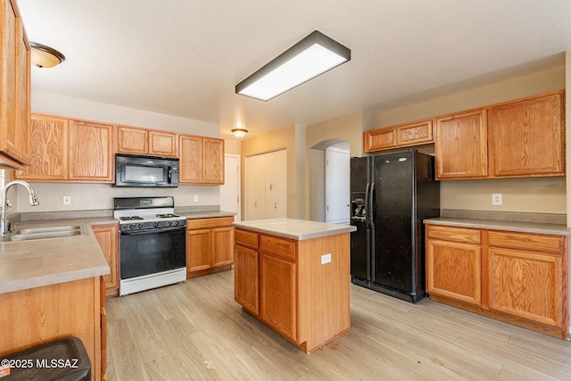 kitchen featuring a center island, sink, light hardwood / wood-style floors, and black appliances