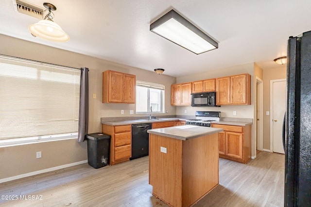 kitchen with sink, hanging light fixtures, a center island, black appliances, and light wood-type flooring