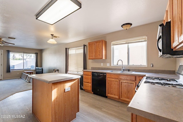 kitchen featuring light hardwood / wood-style flooring, a center island, sink, and black appliances