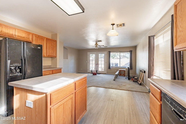 kitchen featuring french doors, decorative light fixtures, light hardwood / wood-style flooring, a kitchen island, and black appliances