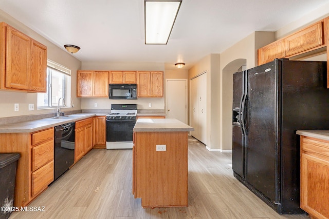 kitchen with light hardwood / wood-style flooring, a center island, sink, and black appliances