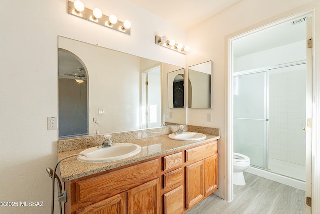 bathroom featuring vanity, a shower with shower door, hardwood / wood-style floors, and toilet