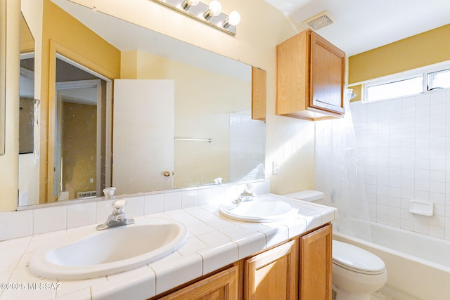 full bathroom with tiled shower / bath, vanity, and toilet