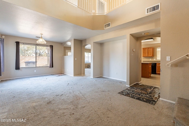 unfurnished living room with light carpet and a high ceiling