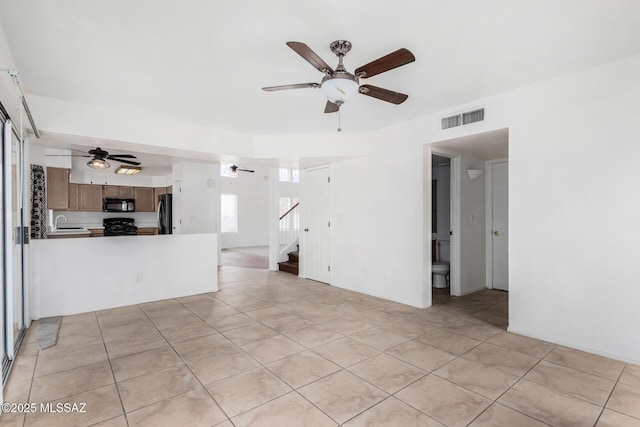 unfurnished living room with sink, light tile patterned floors, and ceiling fan