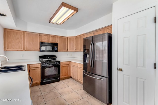 kitchen with sink, light tile patterned floors, black appliances, and light brown cabinets