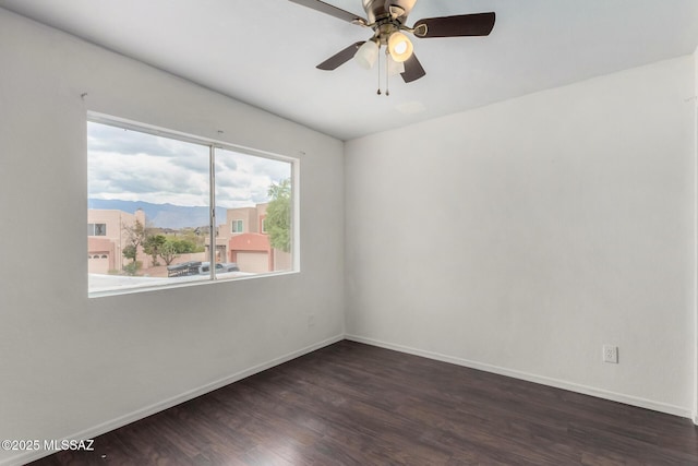 unfurnished room featuring ceiling fan, a mountain view, and dark hardwood / wood-style flooring