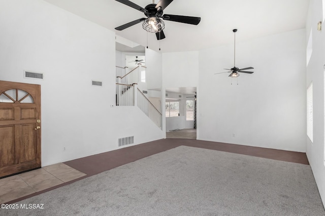 carpeted entryway with ceiling fan and a towering ceiling