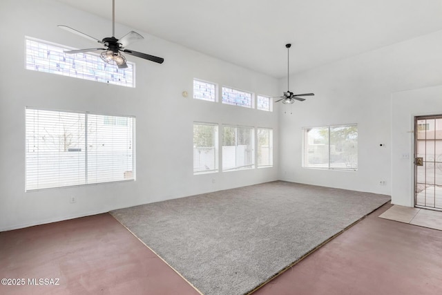 unfurnished living room with carpet, a towering ceiling, and ceiling fan