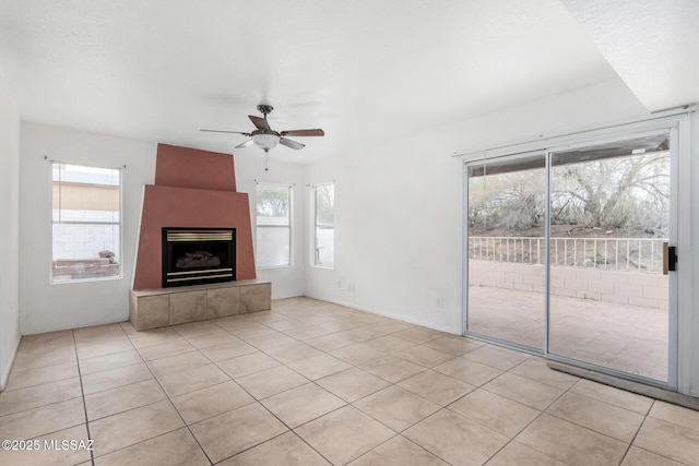 unfurnished living room featuring a tile fireplace, light tile patterned floors, a textured ceiling, and ceiling fan