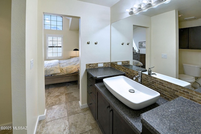 ensuite bathroom with backsplash, toilet, vanity, ensuite bath, and baseboards