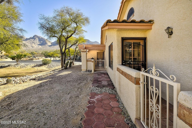 view of exterior entry featuring a gate, a mountain view, and stucco siding