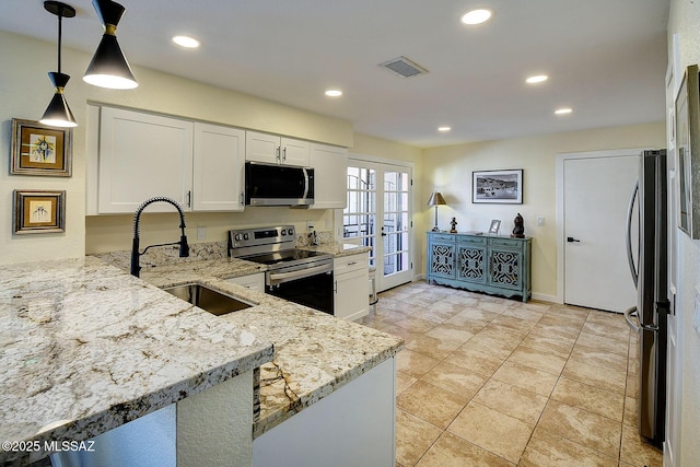 kitchen with light stone counters, stainless steel appliances, hanging light fixtures, white cabinetry, and a sink