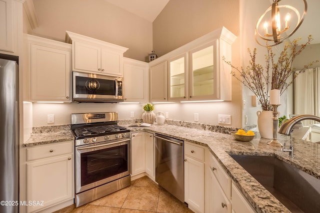 kitchen featuring sink, light tile patterned floors, appliances with stainless steel finishes, pendant lighting, and white cabinets