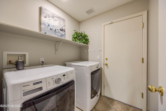 clothes washing area featuring separate washer and dryer and light tile patterned floors