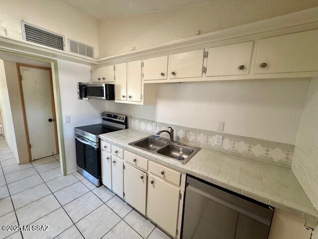 kitchen with white cabinetry, sink, tile counters, and appliances with stainless steel finishes