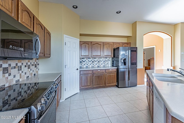 kitchen featuring light tile patterned floors, stainless steel appliances, sink, and backsplash