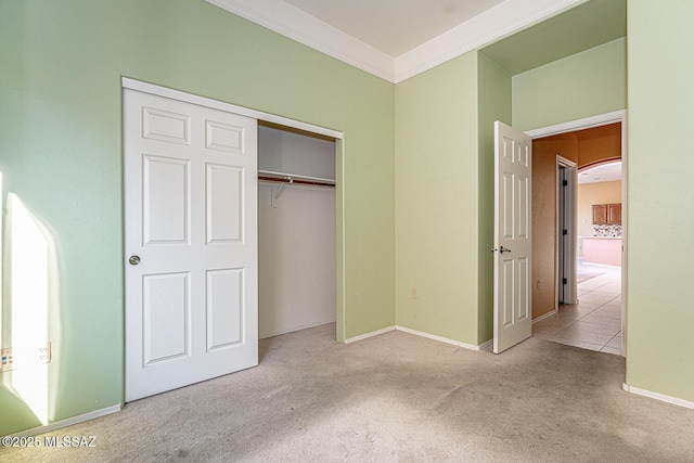 unfurnished bedroom with ornamental molding, light colored carpet, and a closet