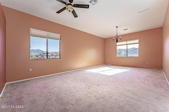 empty room with ceiling fan with notable chandelier, a mountain view, and light carpet