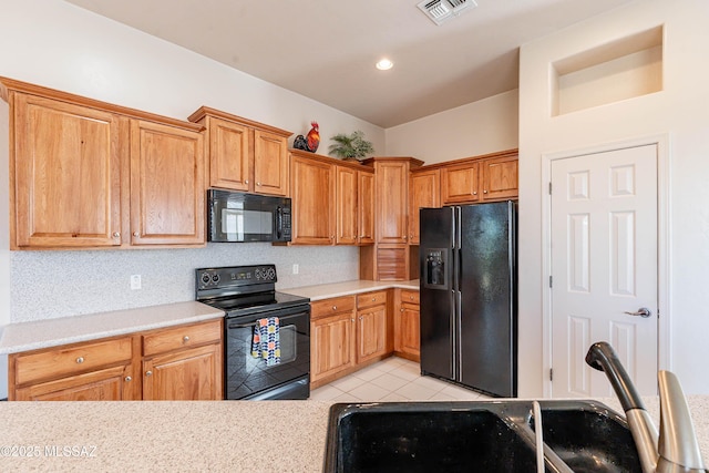 kitchen with light tile patterned flooring, sink, decorative backsplash, and black appliances