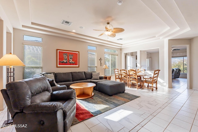 living room featuring a raised ceiling and ceiling fan