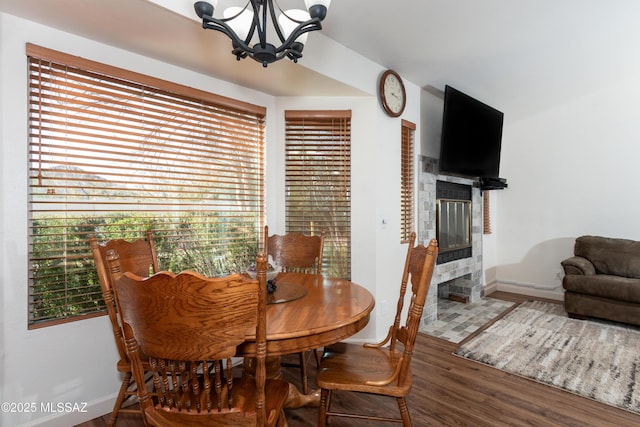 dining area with an inviting chandelier, hardwood / wood-style flooring, and a tile fireplace