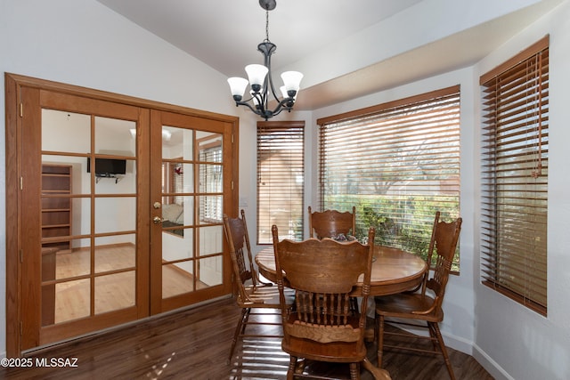 dining room with dark wood-type flooring, vaulted ceiling, french doors, and a chandelier