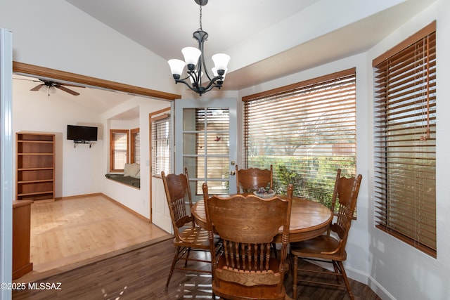 dining area with dark wood-type flooring, ceiling fan with notable chandelier, and vaulted ceiling