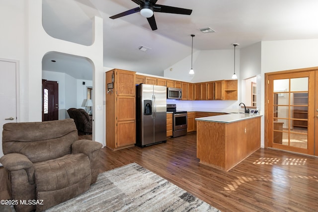 kitchen featuring pendant lighting, sink, kitchen peninsula, stainless steel appliances, and dark wood-type flooring