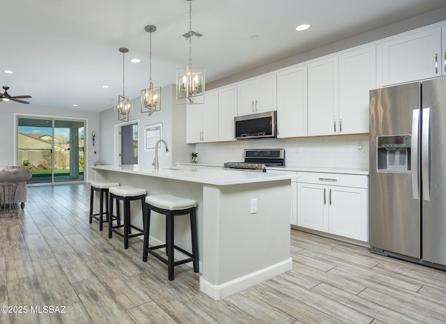 kitchen featuring appliances with stainless steel finishes, sink, a center island with sink, and white cabinets