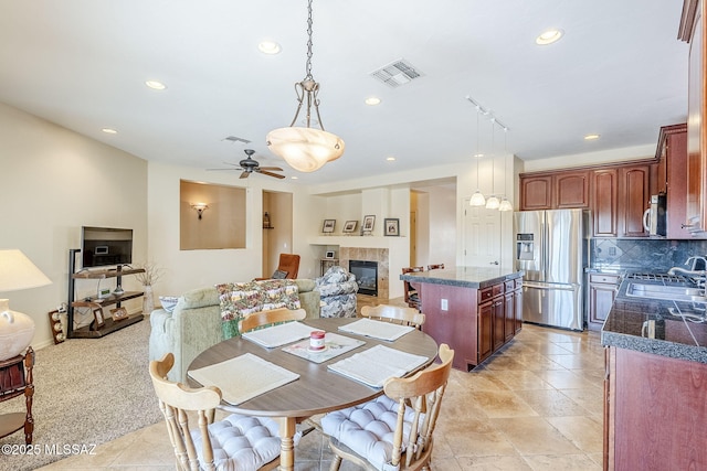 dining space featuring sink, a tile fireplace, and ceiling fan