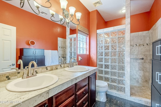 bathroom with tiled shower, vanity, toilet, and a notable chandelier