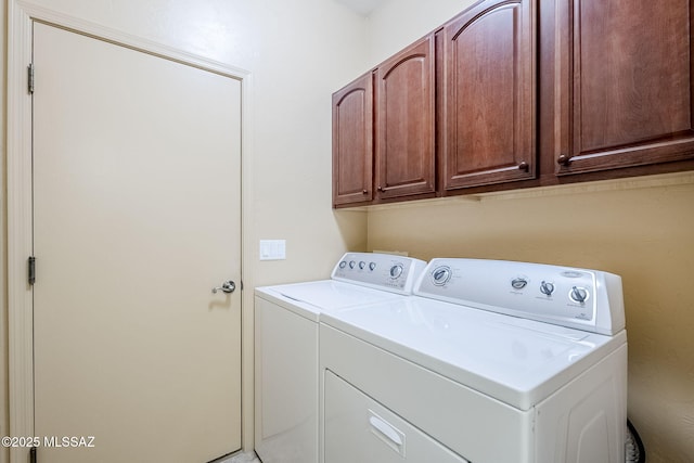 clothes washing area with cabinets and washing machine and dryer