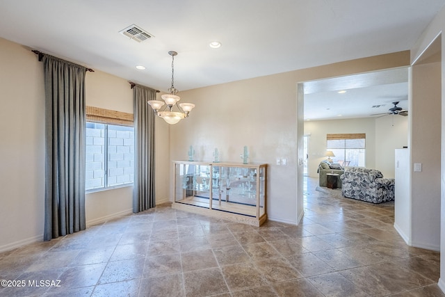 spare room featuring ceiling fan with notable chandelier