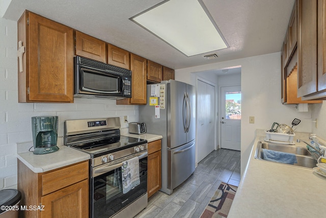 kitchen with tasteful backsplash, appliances with stainless steel finishes, sink, and light wood-type flooring